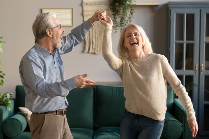 Joyful active old retired romantic couple dancing in living room